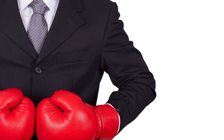 Ein Mann im Anzug trägt rote Boxhandschuhe