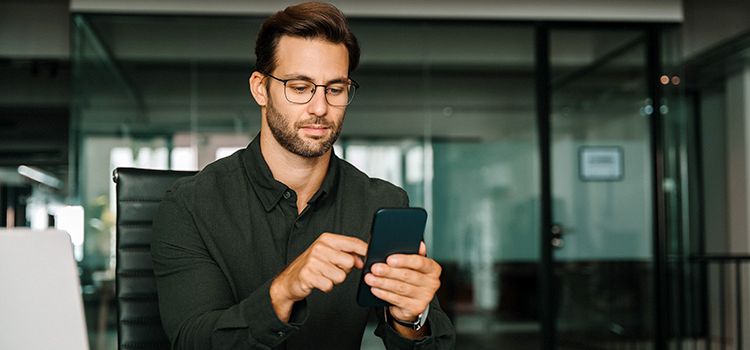 Junger Mann mit seinem Smartphone beschäftigt
