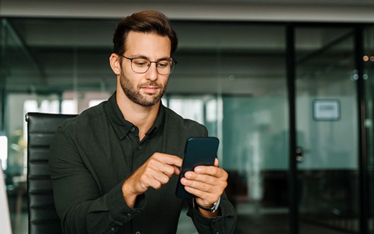 Junger Mann mit seinem Smartphone beschäftigt