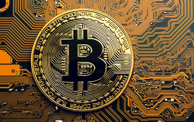 Goldene Bitcoin-Münze liegt auf einem Mainboard