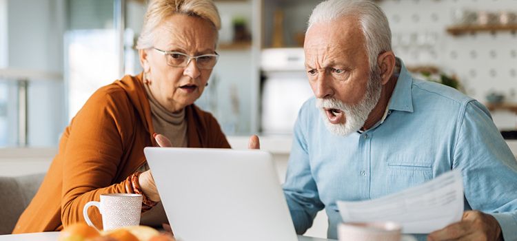 Ein Rentnerpaar schaut gemeinsam entsetzt in den PC
