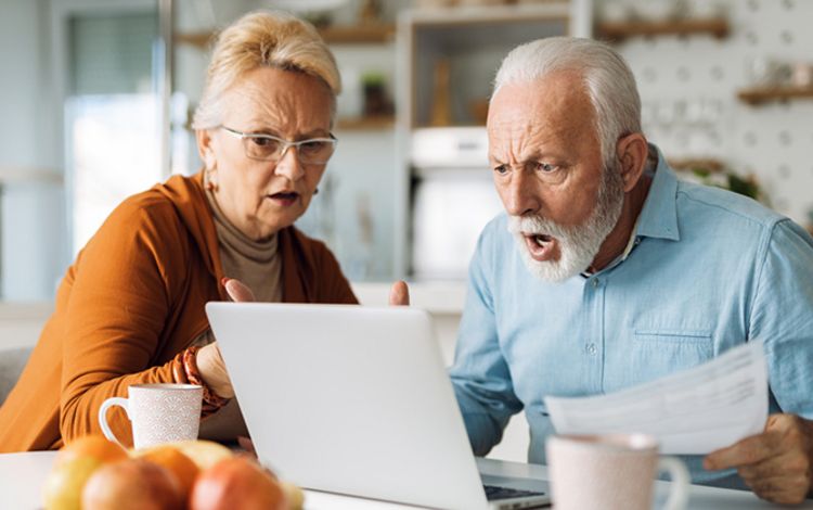 Ein Rentnerpaar schaut gemeinsam entsetzt in den PC