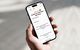 Hand mit Smartphone zeigt die Versicherungs-App Smile