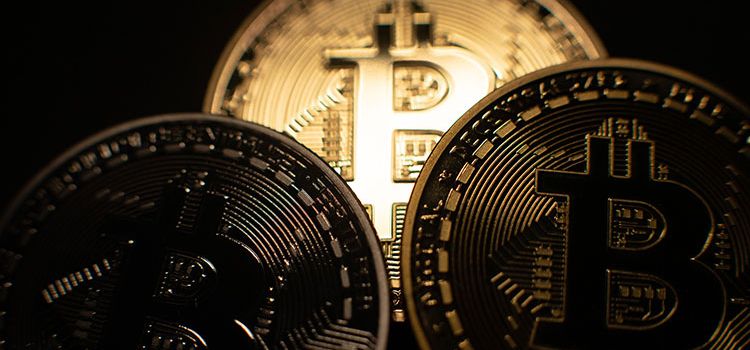 Drei Bitcoin-Münzen im Scheinwerferlicht