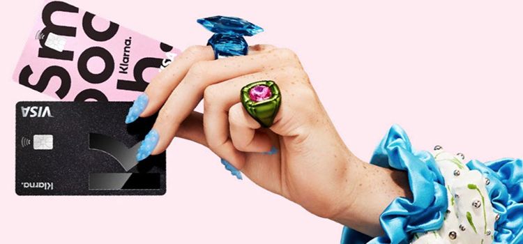 Weibliche Hand mit Ringen trägt eine Klarna-Karte