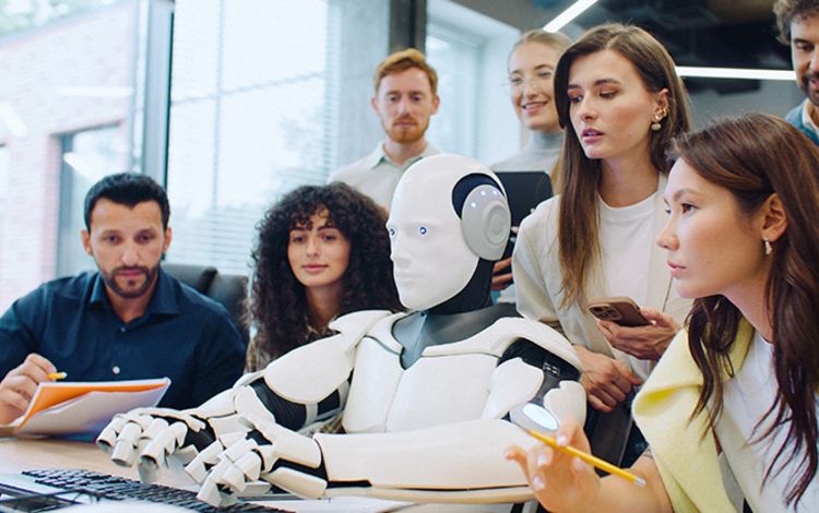 Menschen am PC um einen humanoiden Roboter