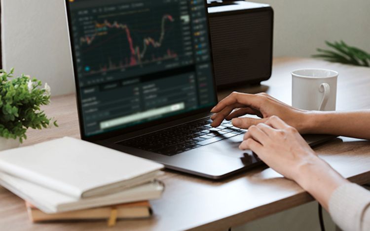 Junge Frau am Laptop beim Traden von Kryptowährungen