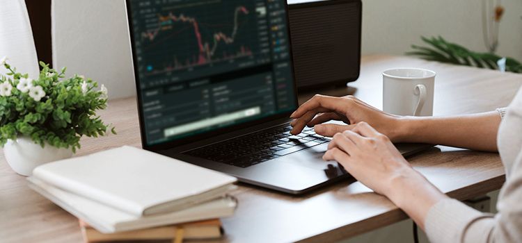 Junge Frau am Laptop beim Traden von Kryptowährungen
