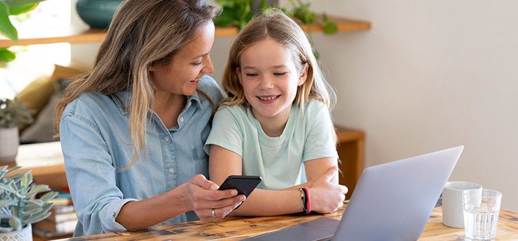 Eine junge Mutter mit Smartphone zeigt ihrer Tochter, wie ihr Portfolio funktioniert