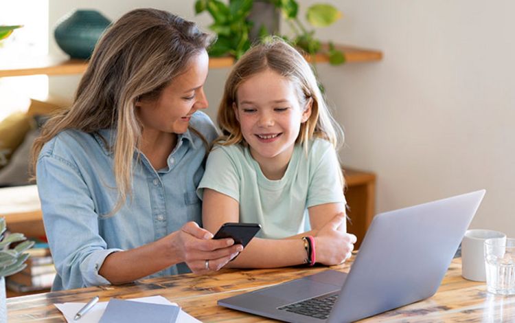 Eine junge Mutter mit Smartphone zeigt ihrer Tochter, wie ihr Portfolio funktioniert