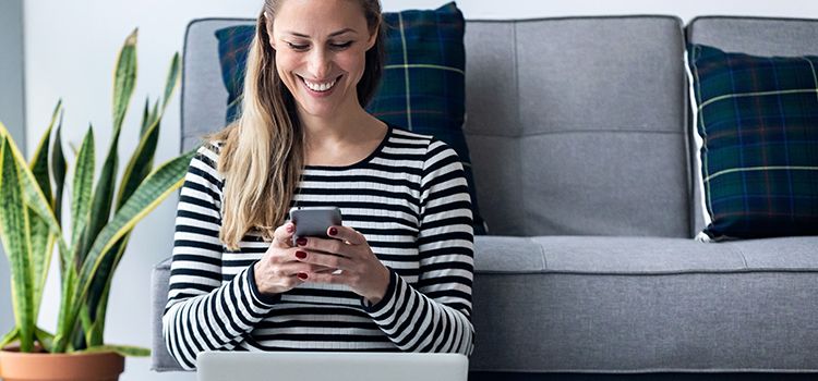 Junge Frau zu Hause am Smartphone und Laptop