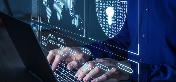 Symbolbild für Cybersecurity, Hände auf Laptop und Monitor mit Sicherheitsmeldungen.