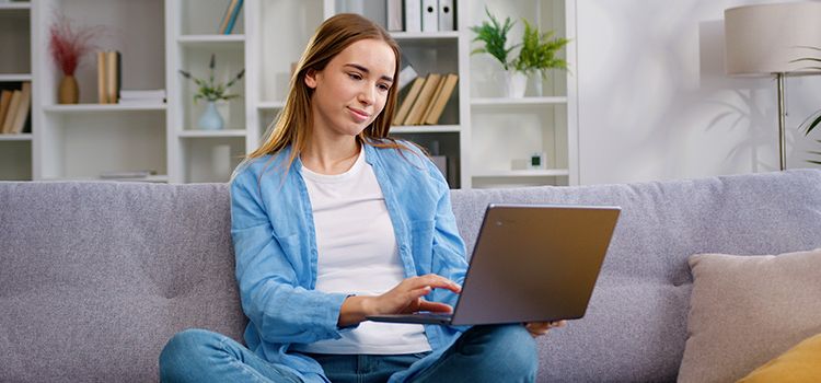 Junge Frau auf Sofa am Laptop