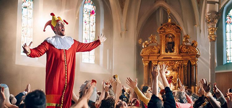 Bild mit einem Kasperli statt einem Priester und begeisterten Zuschauern