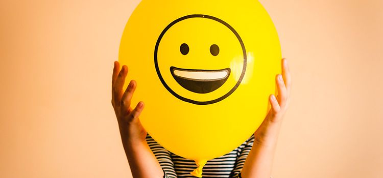 Junge Frau mit Smile-Ballon vor dem Gesicht