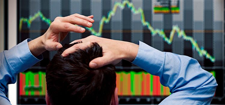 Banker vor dem Monitor sieht fallende Aktienkurse an den Börsen