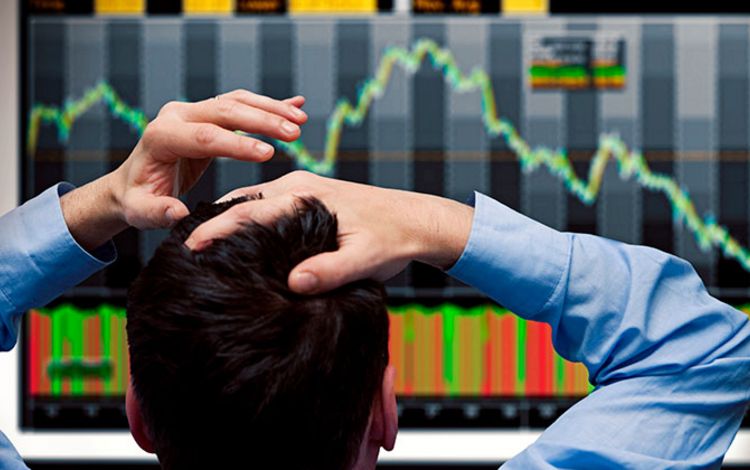 Banker vor dem Monitor sieht fallende Aktienkurse an den Börsen