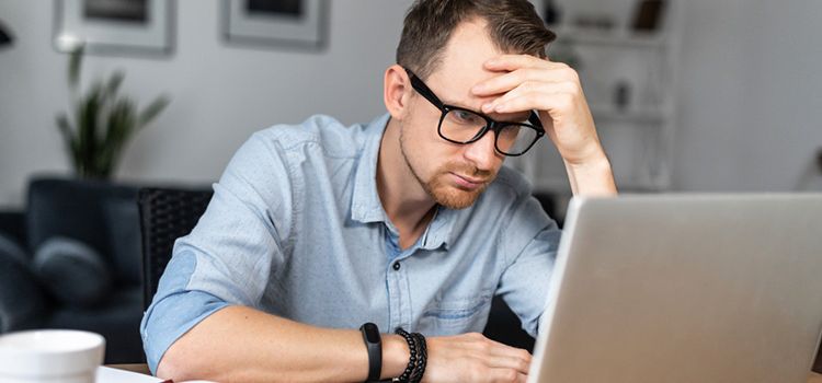 Mann vor dem Laptop mit sorgenvollem Gesicht