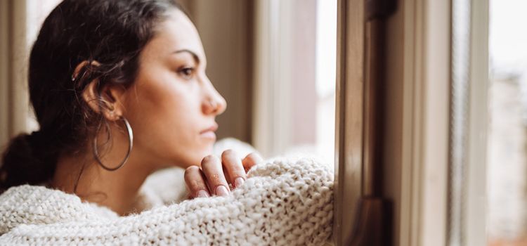 Junge Frau schaut nachdenklich aus dem Fenster