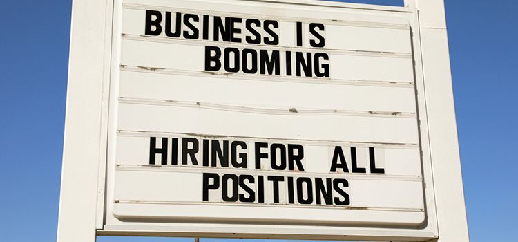 Schild an der Strasse mit Aufschrift: Business is booming, Hiring for all positions