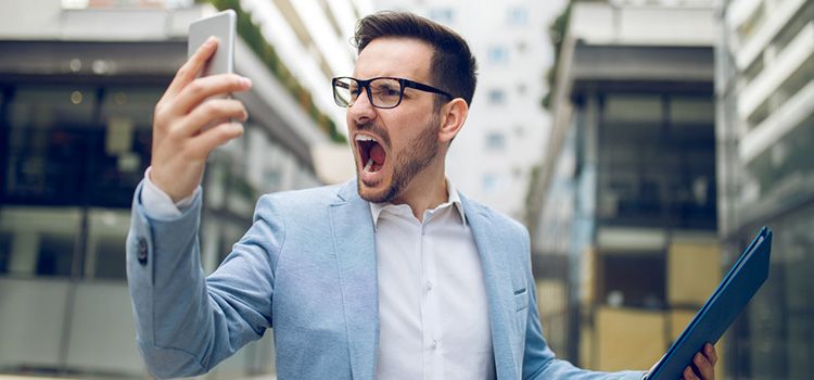 Junger Mann mit Smartphone ärgert sich