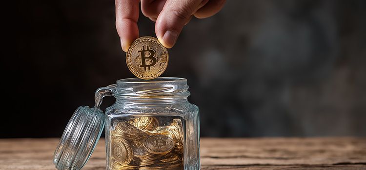 Mann wirft eine Bitcoin-Münze in eine Spardose