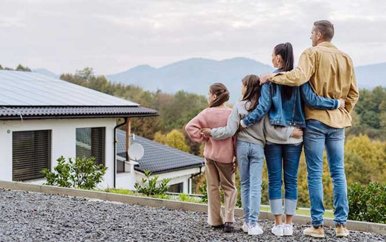 Eine Familie steht vor ihrem Haus und bestaunt die Solaranlage auf dem Dach