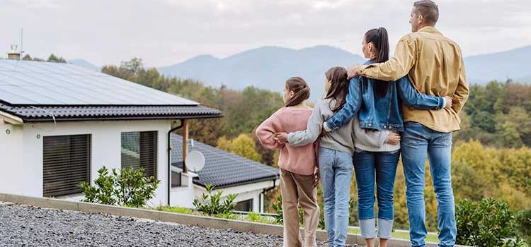 Eine Familie steht vor ihrem Haus und bestaunt die Solaranlage auf dem Dach