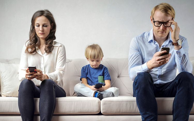 Eltern mit Kind auf Sofa, alle mit Smartphone