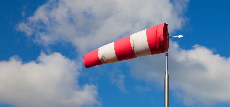 Ein aufgeblähter Windsack vor blauem Himmel und Wolken