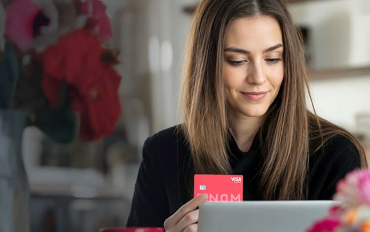 Junge Unternehmerein am Laptop mit Kreditkarte in der Hand