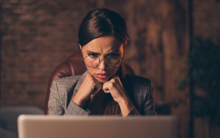 Junge Businesslady am Laptop mit kritischem Blick