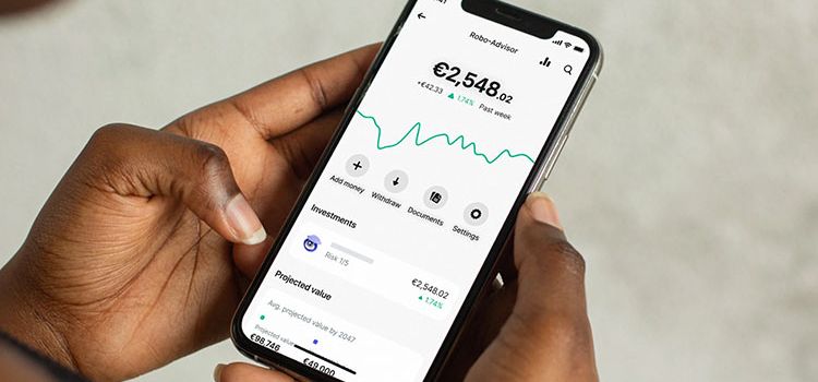 Eine Frau mit Smartphone in der Hand prüft den Robo Advisor in ihrer App