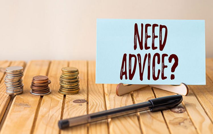 Münzen und Schild mit "Need Advice?" als Symbol für die Notwendigkeit von Finanzberatung
