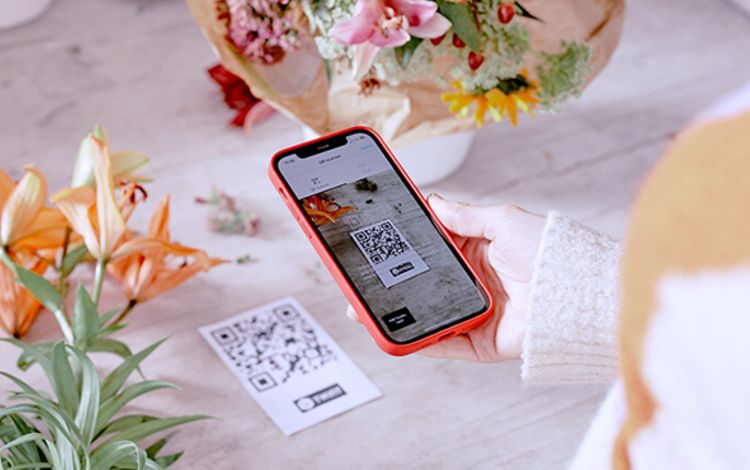Frau mit Smartphone bezahlt über Twint auf dem Handy ihre gekauften Blumen