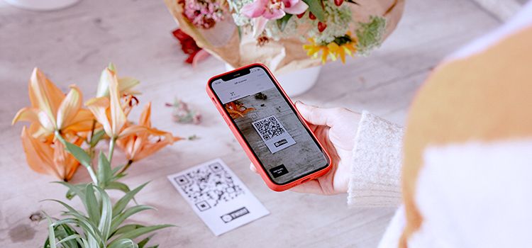 Frau mit Smartphone bezahlt über Twint auf dem Handy ihre gekauften Blumen