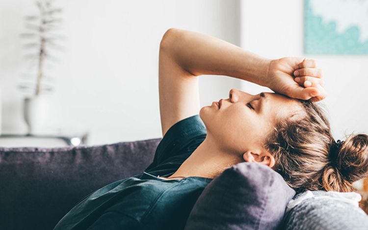 Junge Frau auf dem Sofa, die sich Sorgen macht und sichtbar Depressionen hat