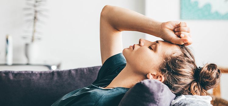 Junge Frau auf dem Sofa, die sich Sorgen macht und sichtbar Depressionen hat