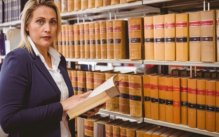 Anwältin liest in einem Buch in der Rechtsbibliothek