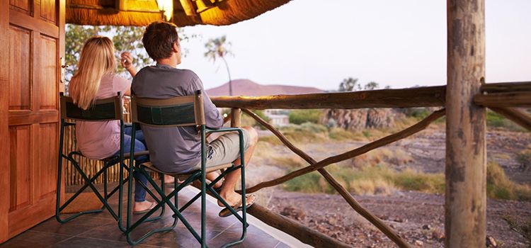 Ein junges Paar sitzt auf einer Veranda aus Holz und blickt in die Steppe.