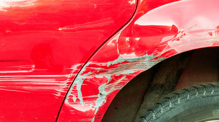 Ein rotes Auto mit einer Delle und Kratzern an der Seite
