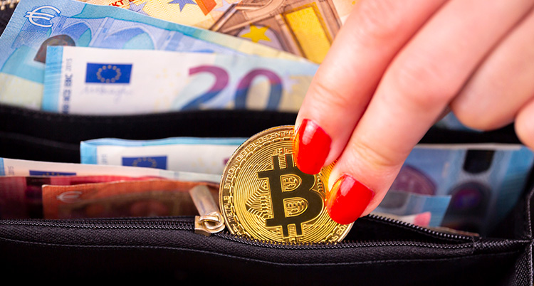 Eine Frau nimmt eine Bitcoin-Münze aus der Brieftasche