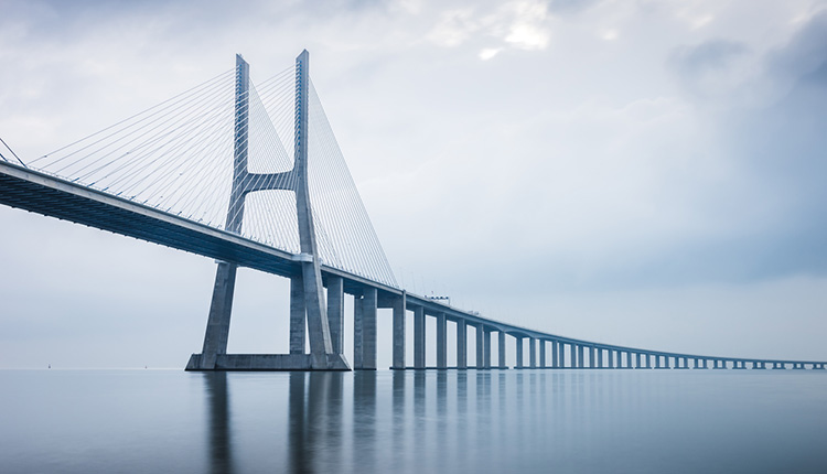 Die Vasco da Gama-Brücke spannt sich bei Sonnenaufgang über das Meer.