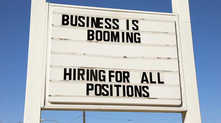 Schild an der Strasse mit Aufschrift: Business is booming, Hiring for all positions