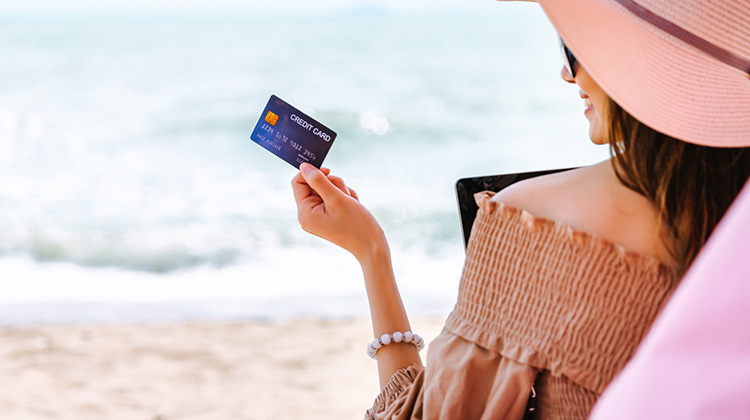 Junge Frau am Strand zahlt mit ihrer Kreditkarte