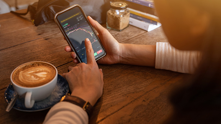 Eine junge Frau prüft ihre Krypto-Bestände au dem Smartphone