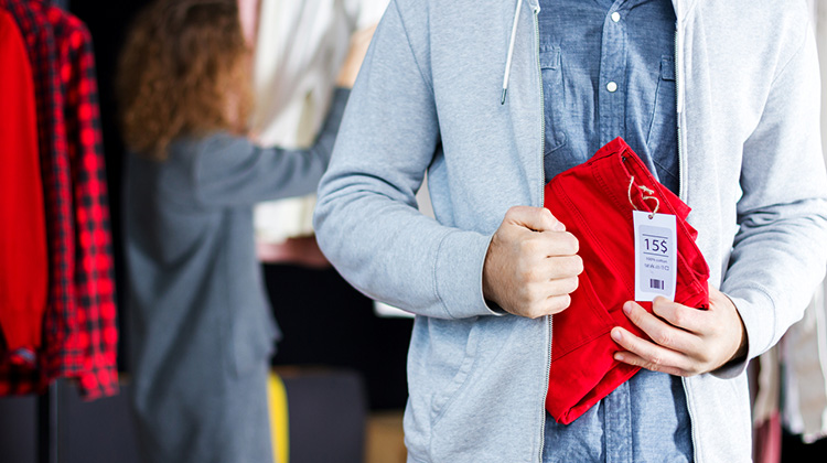 Junger Mann im Laden stiehlt einen Pullover