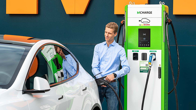 Junger Mann mit Auto an E-Ladestation