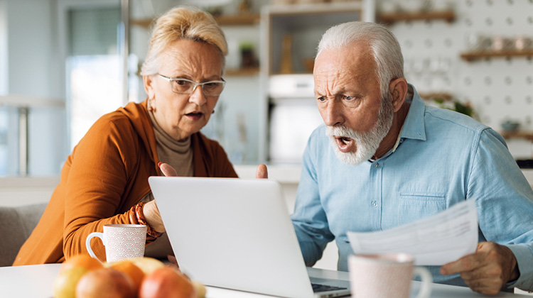 Ein Rentnerpaar schaut gemeinsam entsetzt in den PC