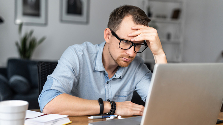 Mann vor dem Laptop mit sorgenvollem Gesicht